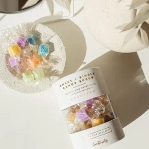 Jar of Assorted Bonblissity Hand Scrubs lies next a dish of the individually wrapped hand scrubs in a variety of colors.