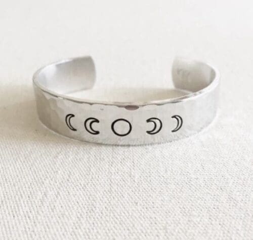 Clair Ashley aluminum cuff bracelet hand-stamped with the phases of the moon. From left, beginning with the new moon, with the full moon centered.