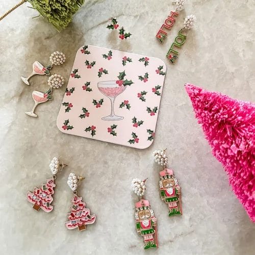 Rhinestone enamel earrings lying on a table with other CANVAS Style enamel holiday earrings, including Nutcrackers and Holly Jolly earrings