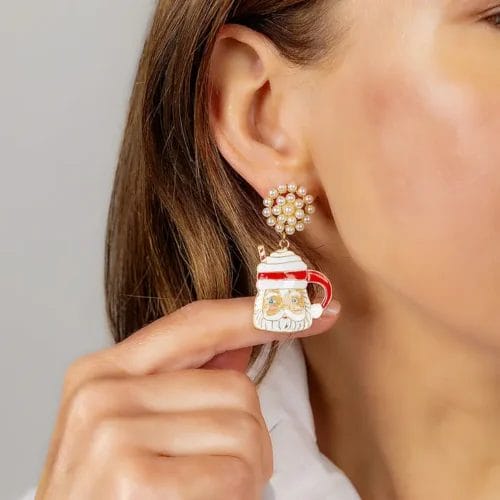 a finger pushes out an enamel Santa mug earring hanging from an earlobe to display it