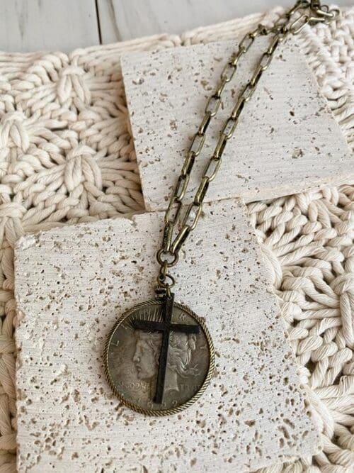 necklace with coin-like pendant and black cross pendant