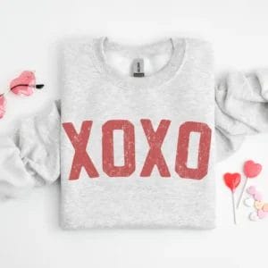 Grey crewneck sweatshirt with XOXO screen-printed in large red font.